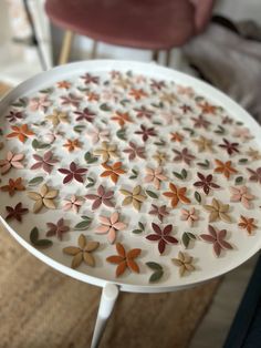 a white table topped with lots of flowers on top of a wooden floor next to a pink chair