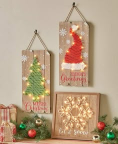 three wooden christmas signs hanging on a wall next to ornaments and presents in front of them