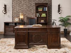 an executive desk with bookshelf and chair in front of brick wall behind it