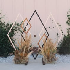 two planters sitting in front of a white building with geometric designs on it's sides