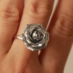 a close up of a person's hand wearing a ring with a rose on it