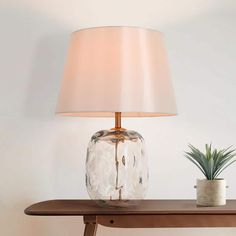 a table with a lamp on it next to a potted plant