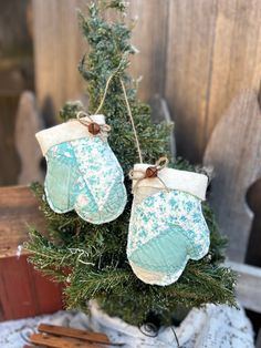 two mittens hanging from a christmas tree with twine and ribbon on it's ends