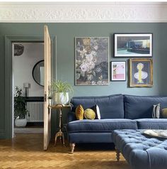 a living room with blue couches and pictures on the wall above them in various frames