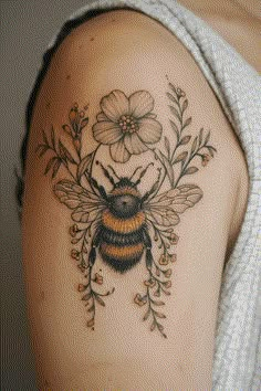 a woman's shoulder with a tattoo of a bee and flowers