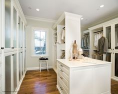 a walk in closet with white cabinets and drawers