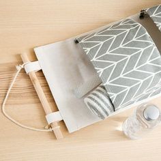 a gray and white bag sitting on top of a wooden table next to an empty bottle