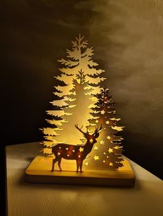 an illuminated deer standing in front of a pine tree with stars on its antlers