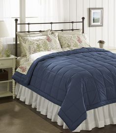 a bed with a blue comforter and white ruffled bedspread