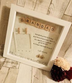 a scrabble frame with the words grandad written on it next to a flower