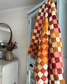 an orange and brown quilt hanging from the side of a cabinet