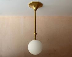 a white ball hanging from the ceiling next to a gold light fixture in a room