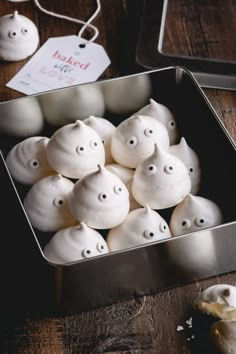 a metal container filled with white marshmallows on top of a wooden table