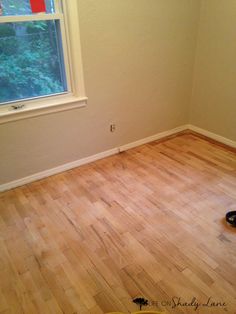 an empty room with hard wood flooring and a window in the corner that is open