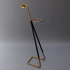 a gold and black metal object on a gray surface with an eyeglass holder in the shape of a tripod