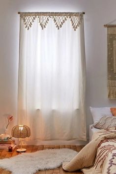 a bed room with a neatly made bed and a white curtain hanging from the ceiling