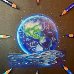 the earth is surrounded by pencils and crayons on a black paper background