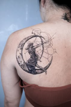 a woman with a tattoo on her shoulder and back, holding an arrow in the center