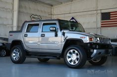 a silver hummer truck parked in a garage next to an american flag on the wall