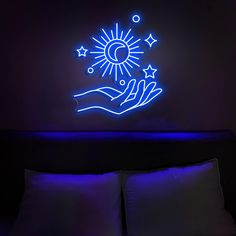 a bed with two pillows and a blue light above it that has a hand holding a star