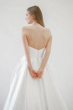 the back of a woman's wedding dress, with her hands on her hips