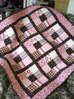 a pink and brown quilt sitting on top of a couch