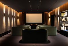 an empty room with two chairs and a projector screen in the corner, along with several bookshelves