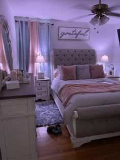 a bedroom with a bed, dresser and tv in the corner is lit up by purple lighting