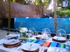 the table is set with plates and silverware for an outdoor dining area that looks like a swimming pool