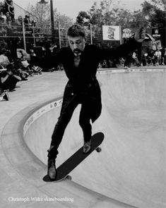 a man riding a skateboard up the side of a cement ramp at a skate park