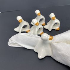 five white ceramic figurines with gold accents on them sitting on a black surface