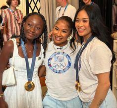 three young women standing next to each other with medals around their necks and smiling at the camera