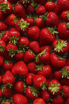 a large group of strawberries with green leaves