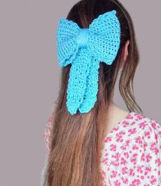 a woman with long hair wearing a blue crochet bow ponytail in front of her head