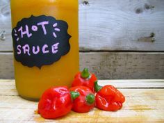 hot sauce in a glass jar next to red peppers