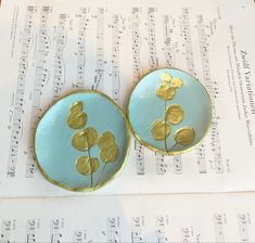 two blue plates with gold leaf designs on top of sheet music paper and musical notes