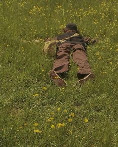 a man laying in the grass with his back to the camera and looking down at him