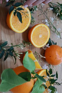 oranges cut in half on a wooden table with leaves and flowers around them,