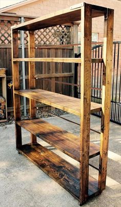 a wooden shelf sitting on top of a cement ground next to a fence and building