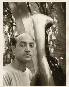 a black and white photo of a man next to a statue