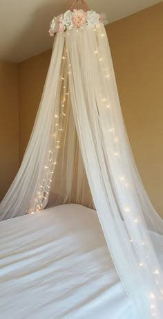 a bed with white sheets and lights on the headboard is decorated with pink flowers