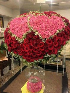 a large bouquet of red and pink roses in a glass vase on top of a table