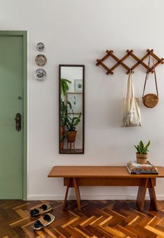 a wooden table sitting under a mirror next to a green door with shoes on the floor