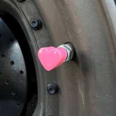 a pink heart shaped object sticking out of the side of a car tire with rivets