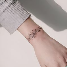 a woman's arm with a small flower tattoo on the left side of her wrist