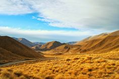 an open field with mountains in the background and a road going through it on either side