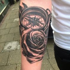 a person with a tattoo on their arm holding a compass and rose in front of them