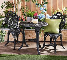 an outdoor table with two chairs and a potted plant in the corner next to it