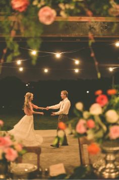 a bride and groom holding hands during their wedding ceremony at night with string lights overhead