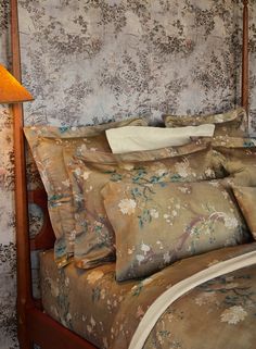 a bed with a wooden headboard and floral wallpaper